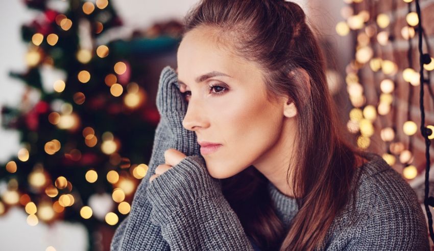 A woman is sitting in front of a christmas tree.