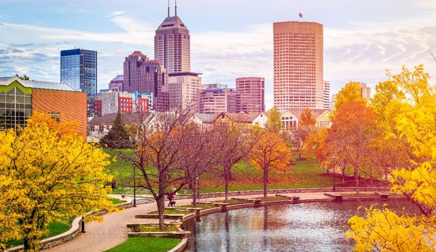 The city of indianapolis is surrounded by trees and a pond.