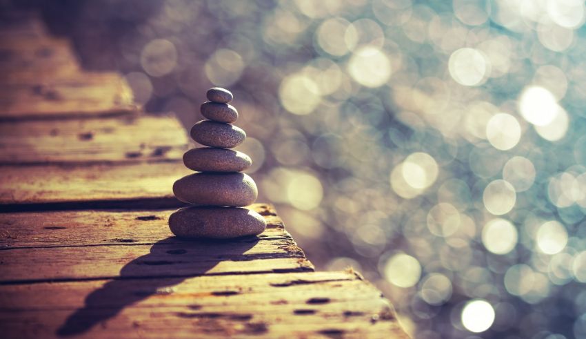 A stack of stones on a wooden deck with bokeh.