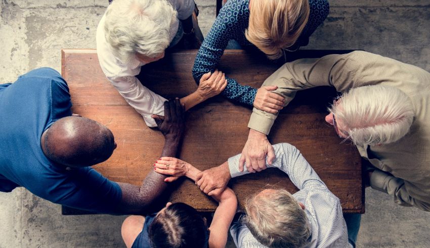 A group of people holding hands around a table.