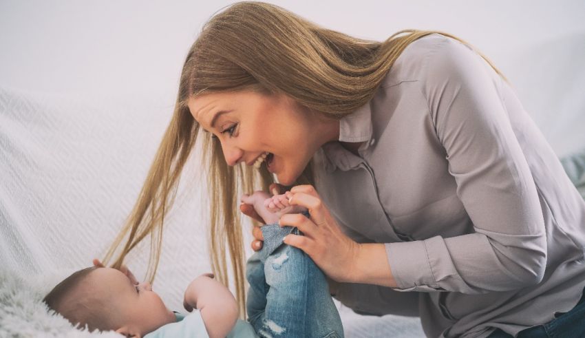 A woman is playing with her baby on the couch.