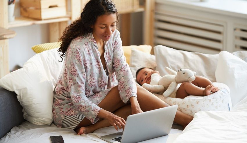 A woman in pajamas using a laptop on a bed.