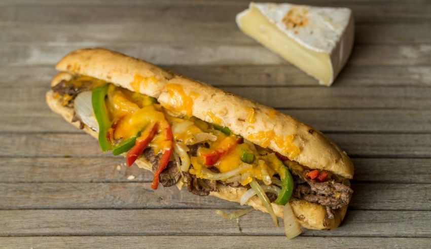 A sandwich with peppers and cheese on a wooden table.