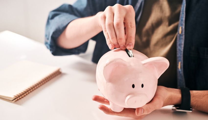 A man is putting money into a pink piggy bank.