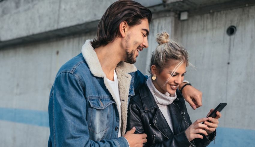 A man and woman are looking at a cell phone.