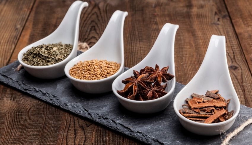 Five spoons of different spices on a slate.