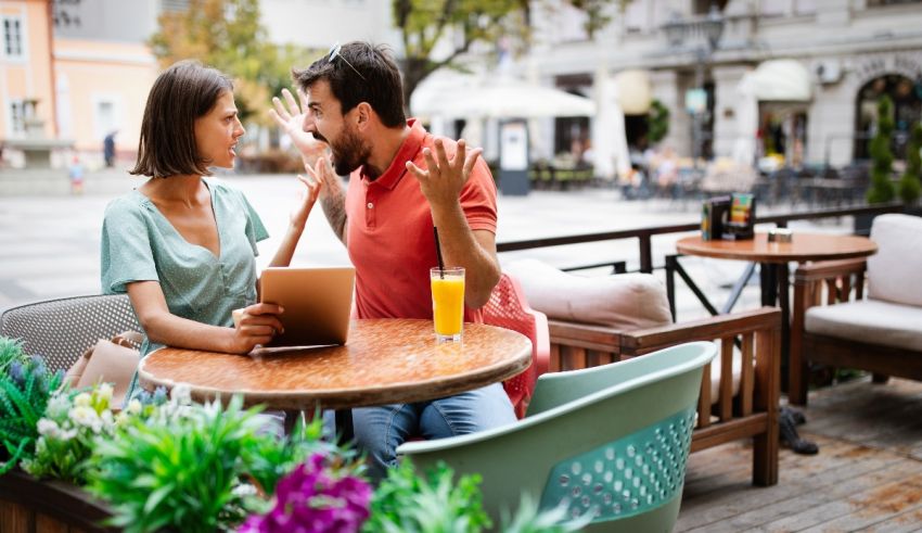 A man and woman sitting at a table in an outdoor cafe.