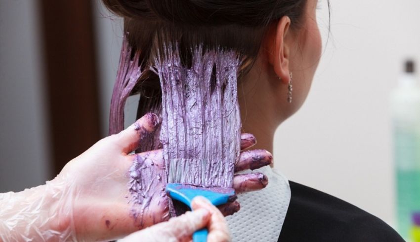 A woman is getting her hair dyed purple.