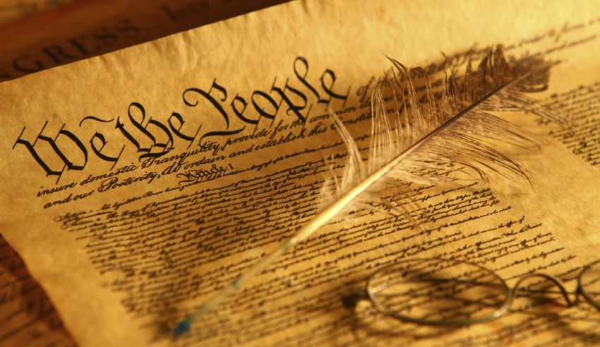 The constitution of the united states with a feather and eyeglasses.