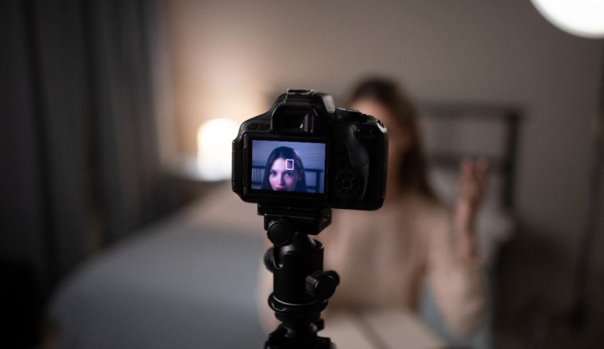 A woman is taking a video of herself in a bedroom.