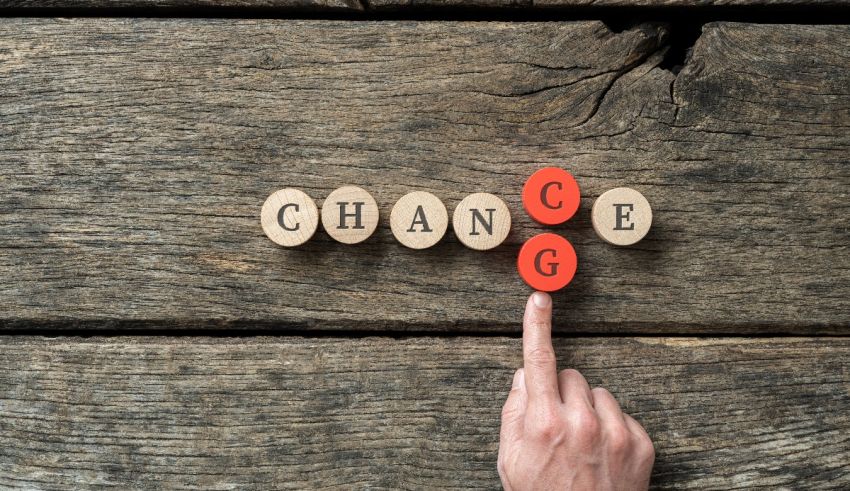 A person pointing to the word change on a wooden background.