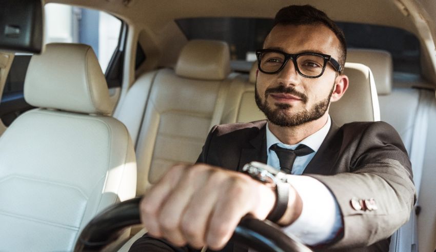 A man in a suit driving a car.