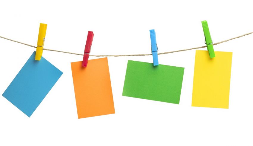 Colorful paper notes hanging on clothesline isolated on white background.