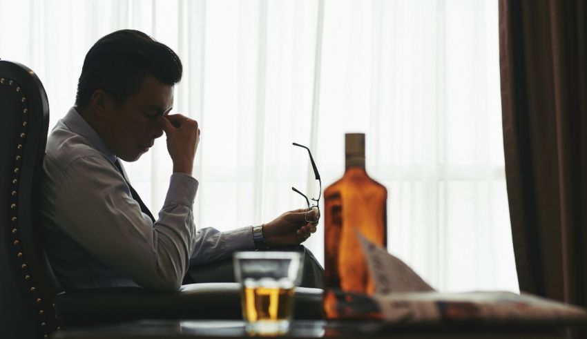 A man sitting in a chair with a glass of alcohol.