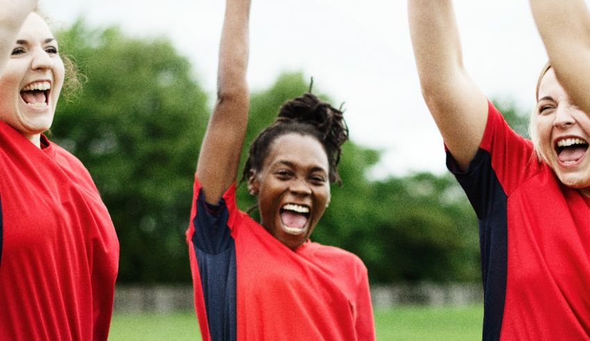 A group of women in red soccer shirts celebrating.