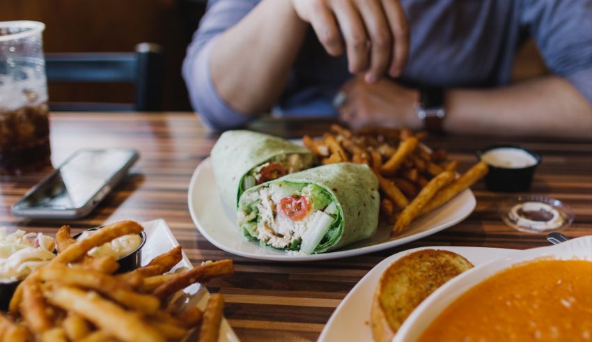 A man sits at a table with a sandwich and fries.