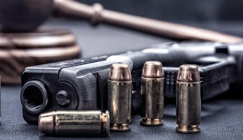 A gun with bullets and a gavel on a table.