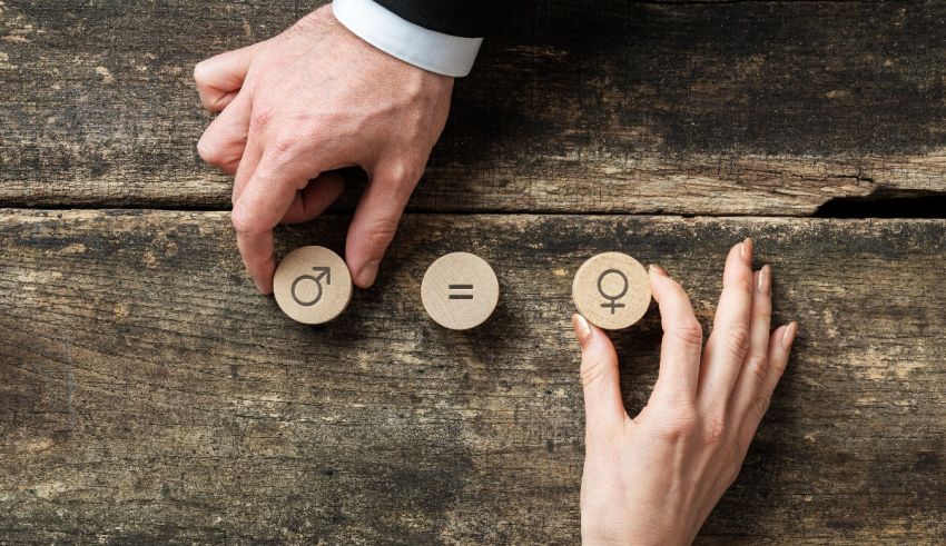 A man and a woman holding wooden sticks with a woman's and a man's symbol on them.