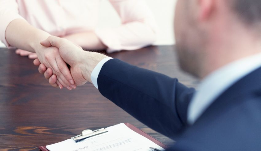 A man and woman shaking hands at a desk.