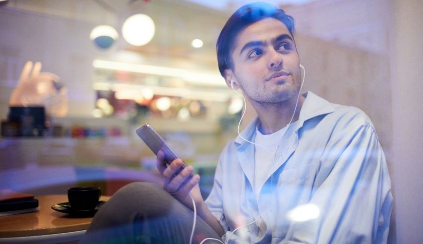 A man is listening to music while sitting in a cafe.