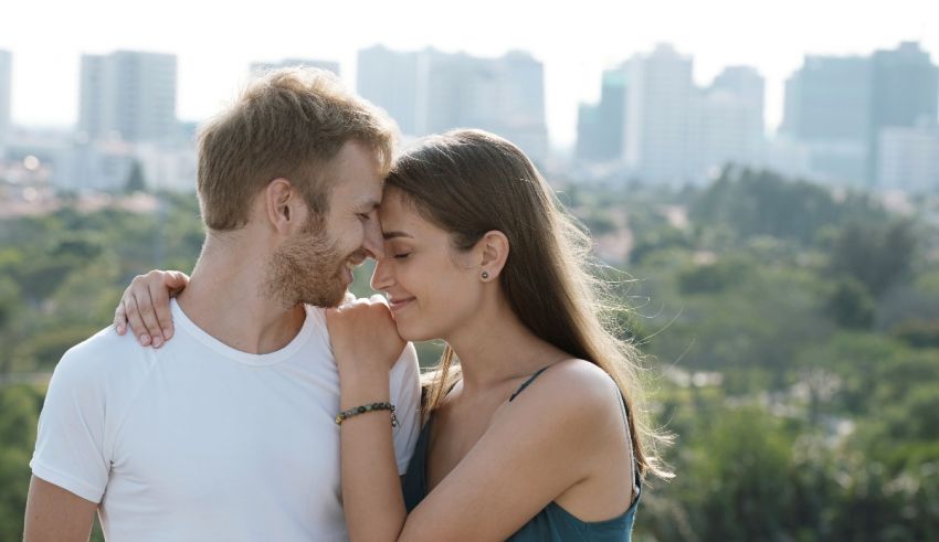 A man and woman are embracing in front of a city.