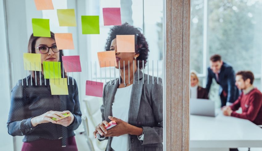 A group of people standing in front of a glass wall with sticky notes.