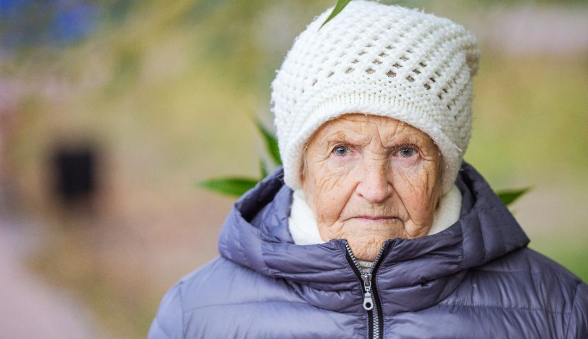 An elderly woman wearing a hat and jacket.