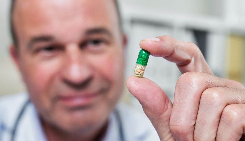 A doctor holding up a green pill.