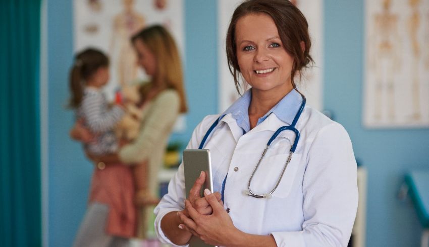 A female doctor holding a tablet in front of a group of people.