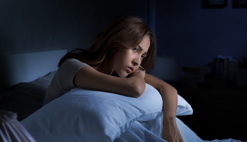 A woman lying in bed at night with her head resting on her pillow.