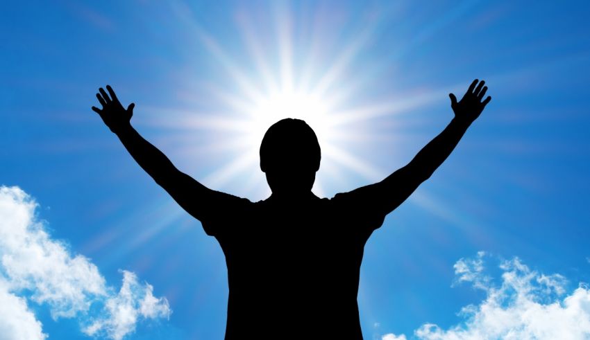 A silhouette of a man with his arms raised in the sky.