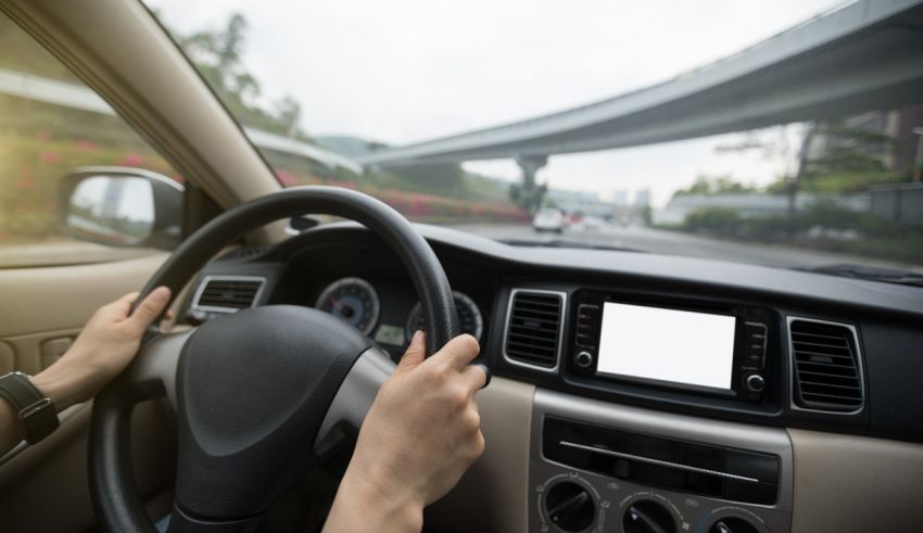 A woman is driving a car with her hands on the steering wheel.