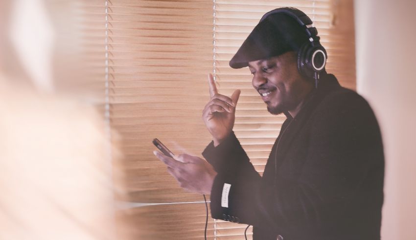 A man in a hat with headphones and a cell phone.