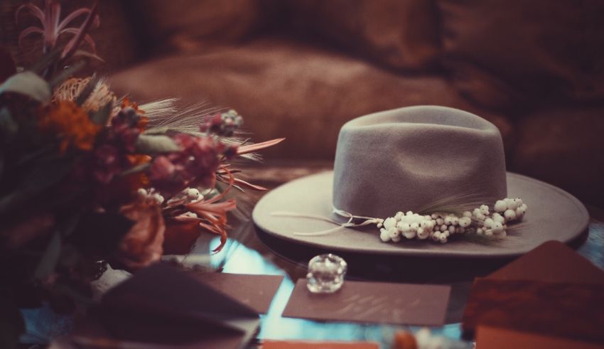 A hat sits on a table next to flowers.