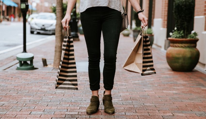 A woman holding shopping bags on a sidewalk.