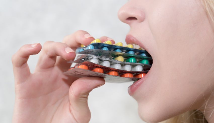 A woman is chewing pills in her mouth.