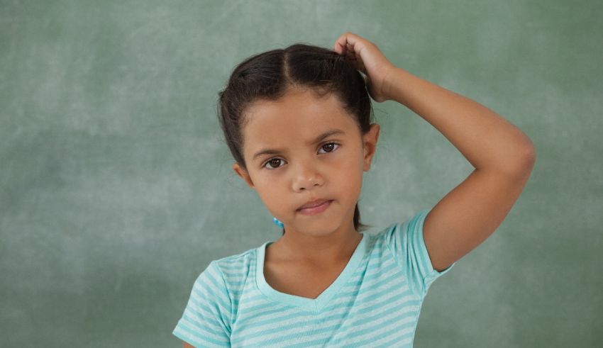 A little girl is standing in front of a chalkboard.