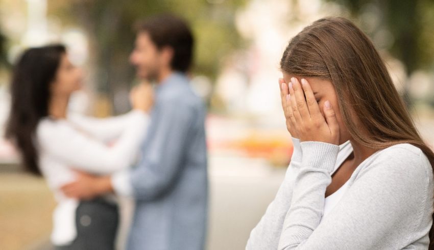 A woman is covering her face while a man is standing next to her.