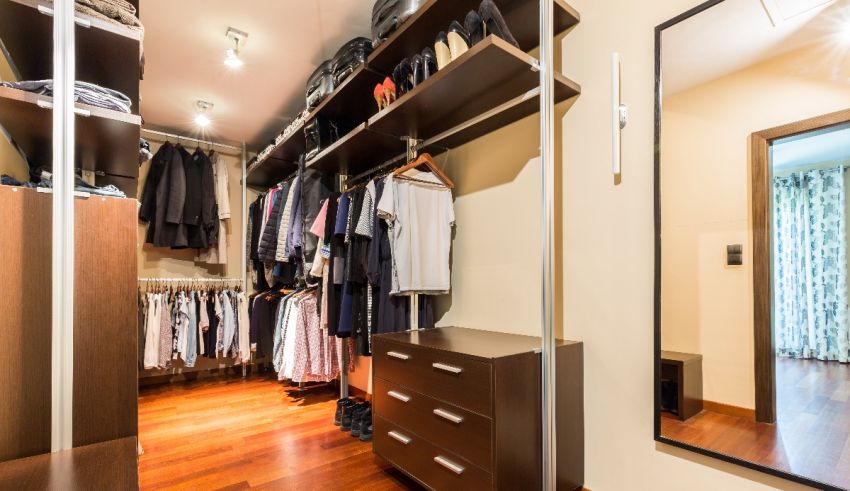 A walk in closet with clothes and a mirror.