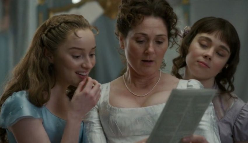 Three women are looking at a book in a room.