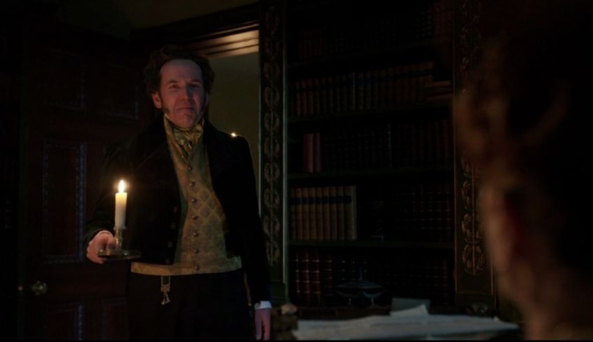 A man is holding a candle in front of a bookcase.