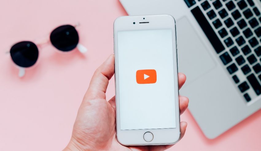 A person holding an iphone with a youtube button on it.