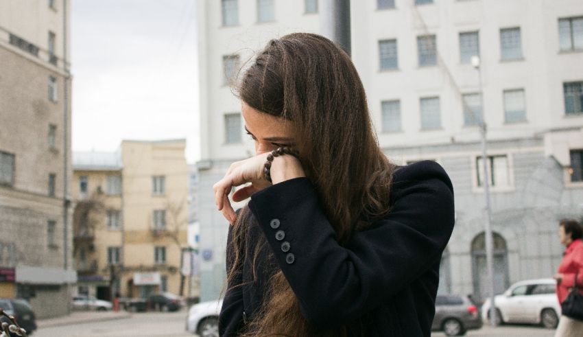 A woman in a black jacket is holding her phone in her hand.