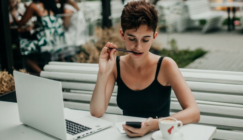 A woman is sitting at a table with a laptop and a cup of coffee.