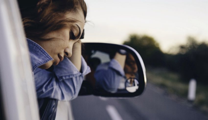 A woman is leaning against the side of a car.