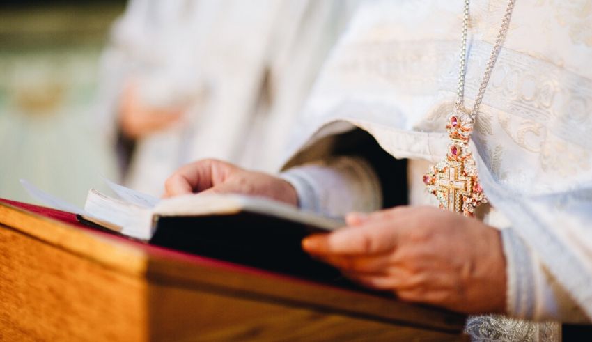 A priest in a white robe is holding a book.