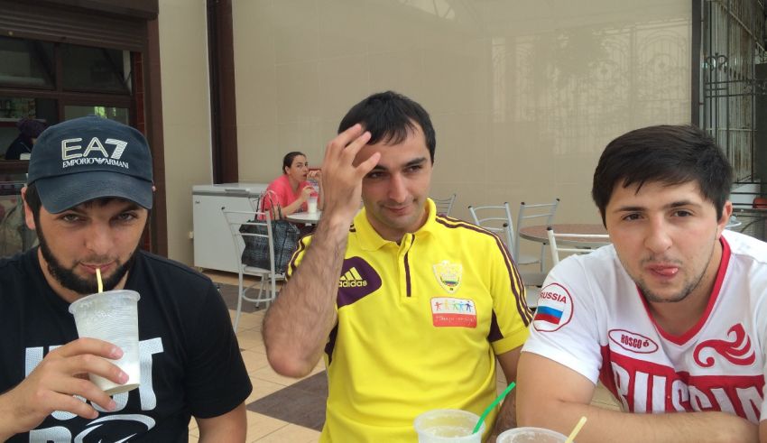 Three men sitting at a table with drinks.