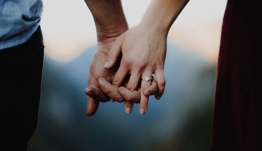 A couple holding hands in front of mountains.