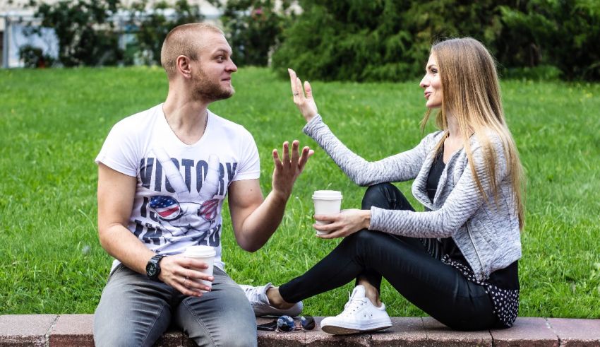 A man and a woman are sitting on a bench in a park.