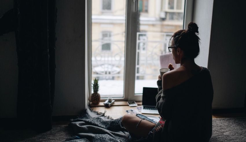 A woman sitting on the floor in front of a window.